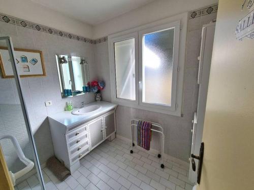 baño blanco con lavabo y ventana en Chez Nelly en La Seyne-sur-Mer