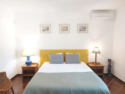 a bedroom with a bed with two tables and two lamps at The Pinewood Villa in Vilamoura