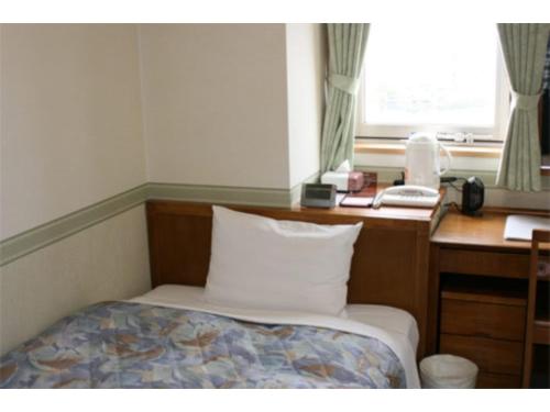1 dormitorio con escritorio, 1 cama y teléfono en Toss Station Hotel Matsuzaka - Vacation STAY 52236v, en Tosu