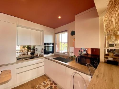 La cuisine est équipée de placards blancs, d'un évier et d'un comptoir. dans l'établissement Charmant T2 moderne près du port de La Teste avec parking, balcon et Wi-Fi - FR-1-474-240, à La Teste-de-Buch