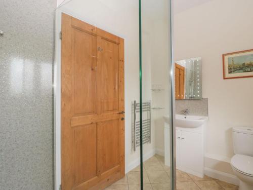 ein Badezimmer mit einer Holztür und einem Waschbecken in der Unterkunft Rectory Farm View in Queen Camel