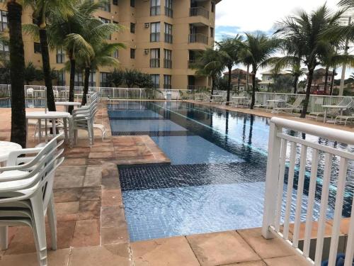 a swimming pool with tables and chairs and a building at Loft Condado em Sahy - Mangaratiba in Mangaratiba