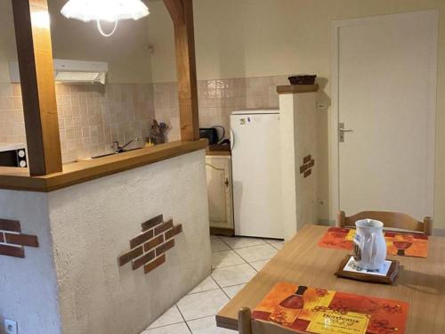 une cuisine avec une table et un réfrigérateur blanc dans l'établissement Charmant gîte rénové avec terrasse privative, jardin et parking - Animaux acceptés - FR-1-489-10, à Neuvy