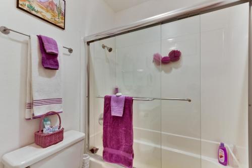 a bathroom with a glass shower with purple towels at Pool View Condo in San Diego