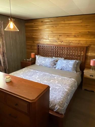 a bedroom with a large bed with a wooden wall at Cozy lake cottage in Wabamun