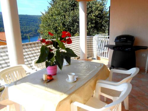 una mesa con un jarrón con una flor en un porche en Villa Luma Apartments en Labin