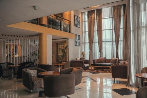 a lobby with chairs and tables and windows at Sidra International Hotel in Addis Ababa