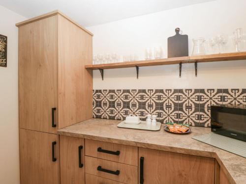 a kitchen with wooden cabinets and a tile wall at Beau Hideaway in Dorchester