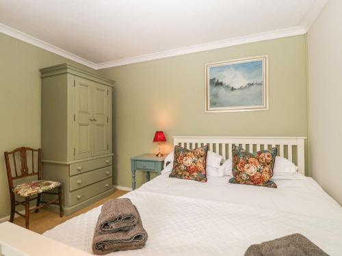 a bedroom with a white bed and a chair at Beau Hideaway in Dorchester