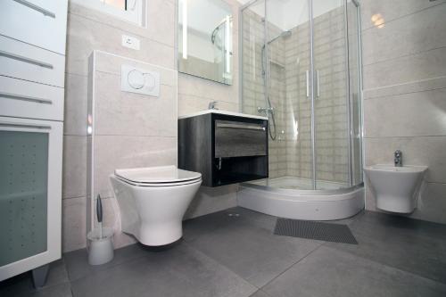een badkamer met een toilet, een wastafel en een douche bij Vila Stella in Tisno