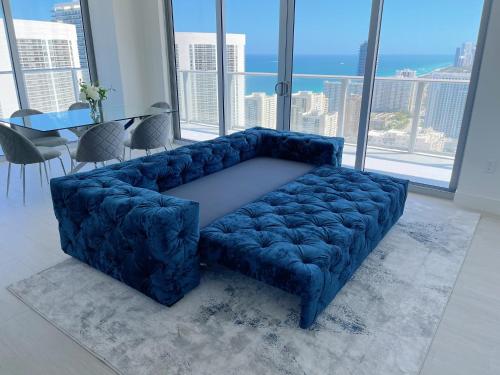a blue couch in a living room with a large window at HYDE BEACH HOUSE - MILLIONAIRE 2 bd 2 ba APT, DIRECT OCEAN VIEW, 5 MIN WALK TO OCEAN in Hollywood