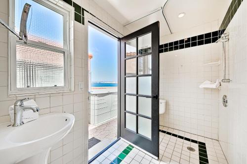 a bathroom with a sink and a shower with a window at On The Beach Casa in San Diego