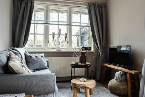 a living room with a couch and a window at Gastenverblijf De Weldadigheid in Eesveen