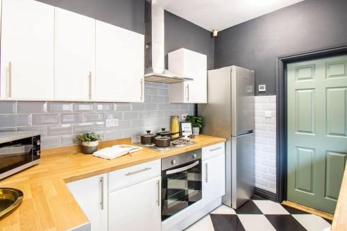 a kitchen with white cabinets and a green door at Ashford House - By Sigma Stays in Etruria