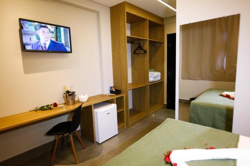 una habitación de hotel con TV en la pared en NEO PARK HOTEL, en Maringá