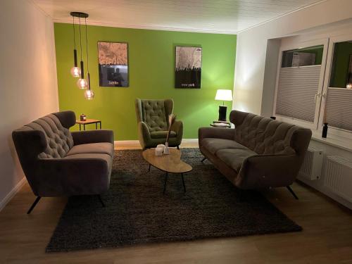 a living room with two couches and green walls at Ferien Bungalow Ennens in Rhauderfehn