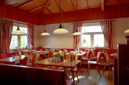 a dining room with tables and chairs and windows at Stiefelburg Der Berghof in Nauendorf