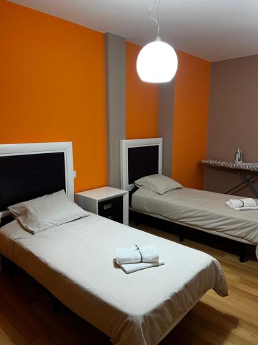 twee bedden in een kamer met oranje muren bij Casa del tiempo in Vecindario