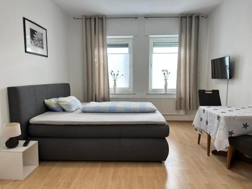 1 dormitorio con cama, mesa y ventanas en Haus Medaillon, en Hamm