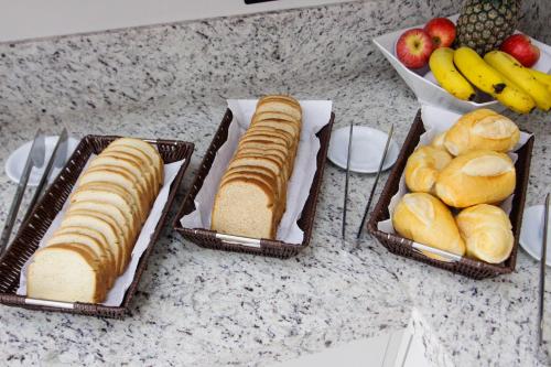 tres cestas de pan y fruta en un mostrador en NEO PARK HOTEL en Maringá