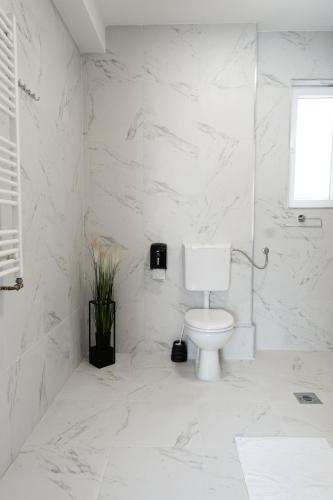 a white bathroom with a toilet and marble walls at Key Apartments in Novi Sad