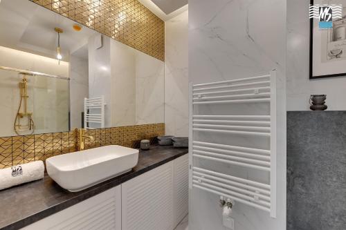 a white bathroom with a sink and a mirror at MS Apartments Rest 4.0 in Sopot