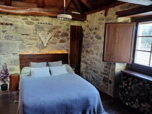 a bedroom with a bed in a stone wall at El Cuarto in Suarbol