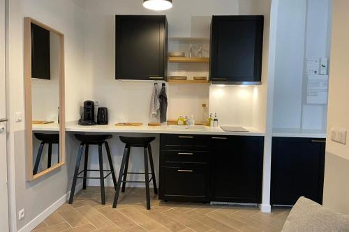 a kitchen with black cabinets and a white counter top at Black Serenity Suites Studio near Paris Orly in Thiais