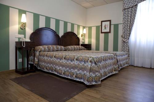 Hotel Doña Jimena في فيلاركايو: غرفة نوم بسرير وشراشف خضراء وبيضاء