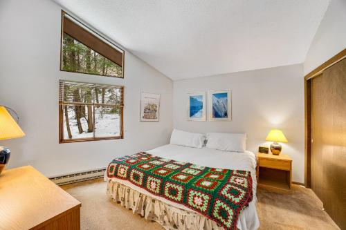 a bedroom with a bed and two windows at Dwight Road Getaway in Quechee