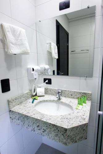 a bathroom with a sink and a mirror at NEO PARK HOTEL in Maringá