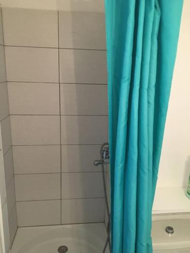 une douche avec un rideau de douche bleu dans une salle de bain dans l'établissement Très beau studio au Grau du Roi tout équipé 33m2, au Grau-du-Roi