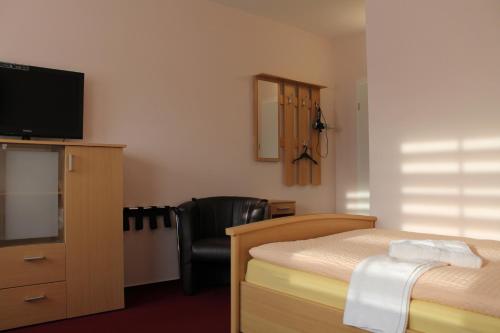 a bedroom with a bed and a television and a chair at Hotel Pension Schwerin-Haus Schreiber in Schwerin