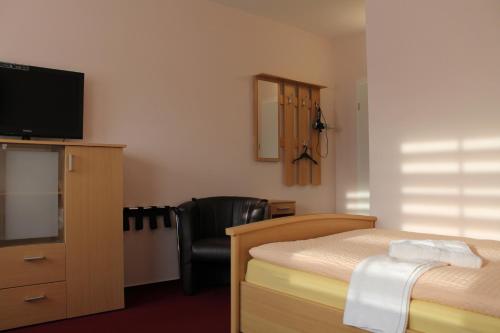 ein Schlafzimmer mit einem Bett, einem TV und einem Stuhl in der Unterkunft Hotel Pension Schwerin-Haus Schreiber in Schwerin