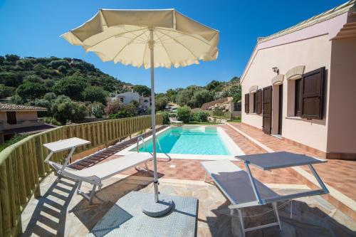 un patio con 2 sillas y una sombrilla junto a la piscina en Villa Ara, en Torre delle Stelle
