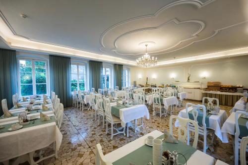 a dining room with white tables and white chairs at Hotel Goldener Stern in Caldaro