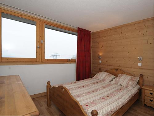 a bedroom with a bed and a table and two windows at Appartement Les Menuires, 2 pièces, 5 personnes - FR-1-344-856 in Les Menuires