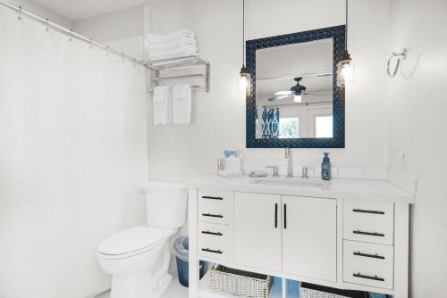 a white bathroom with a toilet and a mirror at Makarios Beach Blu in Navarre