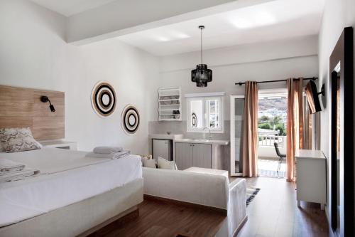 a white bedroom with a large bed and a kitchen at Cactus Suites Kythnos in Mérikhas