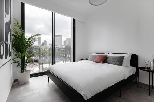 um quarto branco com uma cama e uma grande janela em Gorgeous 3 bedrooms, Parking , New building em Tel Aviv