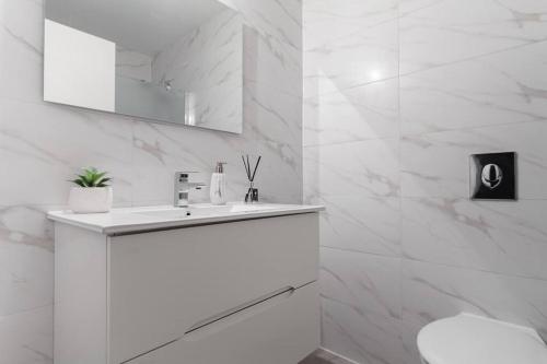 ein weißes Badezimmer mit einem Waschbecken und einem Spiegel in der Unterkunft Gorgeous 3 bedrooms, Parking , New building in Tel Aviv