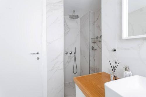 a white bathroom with a shower and a sink at Cozy apartments in the heart of Neve Tzedek in Tel Aviv