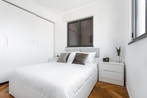 a white bedroom with a white bed and a window at Cozy apartments in the heart of Neve Tzedek in Tel Aviv