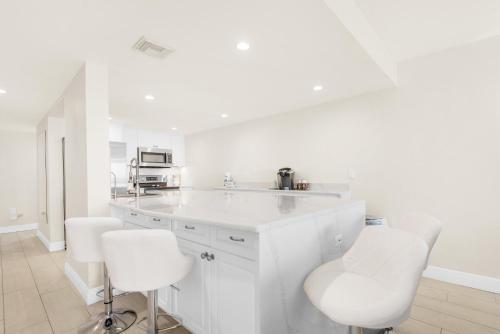 a white kitchen with white cabinets and white stools at Santa Rosa Dunes 425 in Pensacola Beach