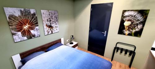 a bedroom with a blue bed and three pictures on the wall at Inntermezzo in Almere