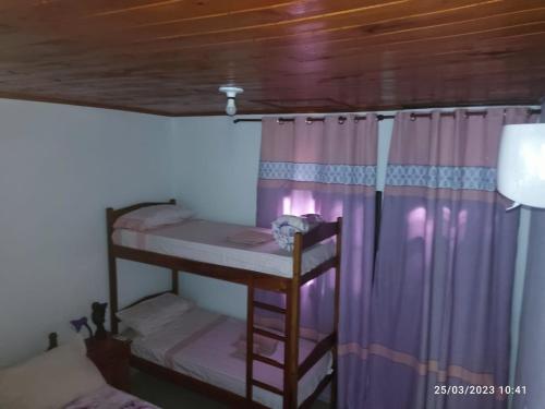 um quarto com 2 beliches e cortinas roxas em Miguel Departamentos 2 em Puerto Iguazú