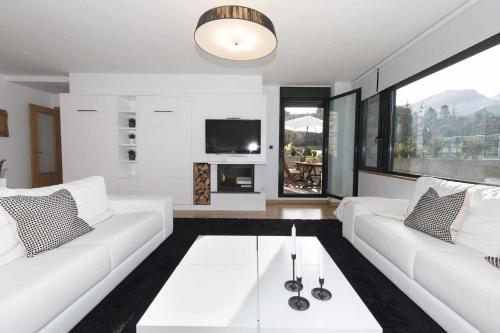 uma sala de estar com sofás brancos e uma televisão em Balcón de Saras by BeValle em Panticosa