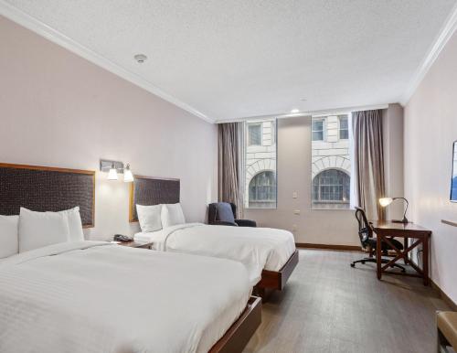 a hotel room with two beds and a desk at Wyndham Garden Baronne Plaza in New Orleans