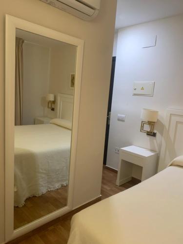 einen Spiegel in einem Zimmer mit einem Bett und einem Bett sidx sidx sidx sidx in der Unterkunft Hostal Plaza in Marmolejo