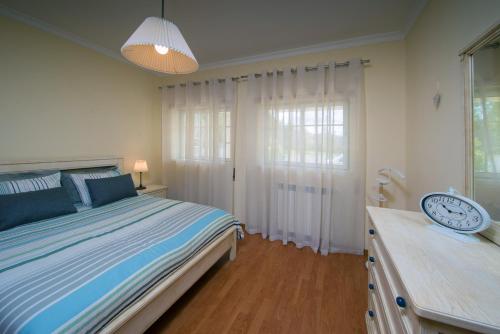 1 dormitorio con 1 cama y reloj en una cómoda en Quinta dos Silvas - Piscina, en Ansião